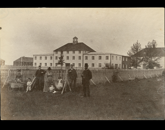 photo of a group of men, women, and children standing in front of a building